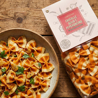 Pasta dish with a box of farfallepasta on a wooden surface
