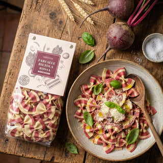 A packet of colourful farfalle pasta next to. aprepared dish