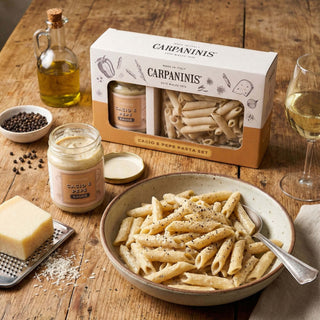 A Carpaninis cacio e pepe gift set on a wooden table with a pepared bowl