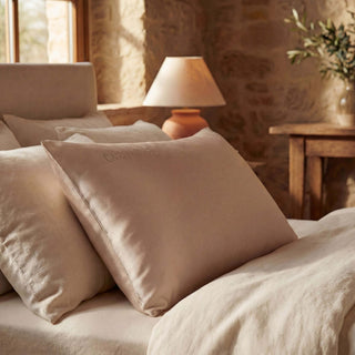 Beige pillows on a bed with a warm-toned room in the background