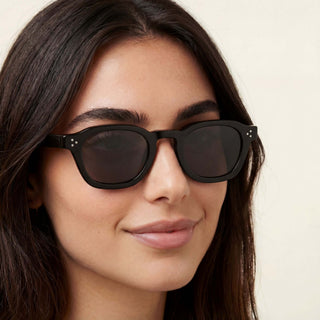 Woman wearing black sunglasses with a neutral background