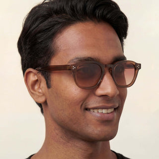 Man wearing brown sunglasses with a neutral background