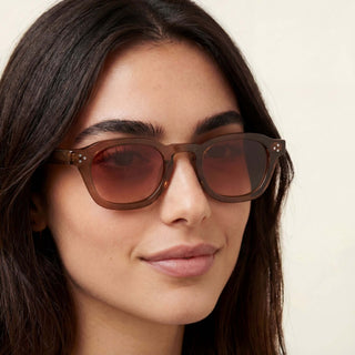 Close-up of a person wearing brown sunglasses with a neutral background
