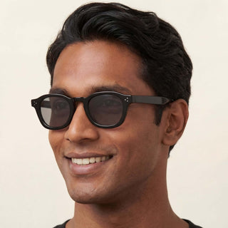 Man wearing dark sunglasses with a neutral background