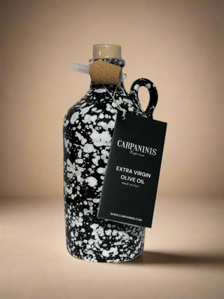 A Carpaninis handmade bottle of extra virgin olive oil from Italy. Painted black with a white splatter.
