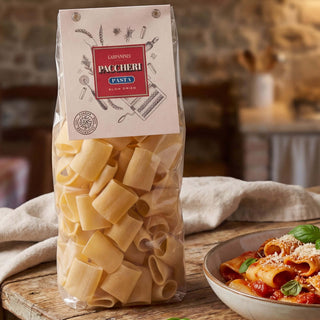 A packet of Carpaninis Paccheri pasta on a wooden table in a Tuscan kitchen