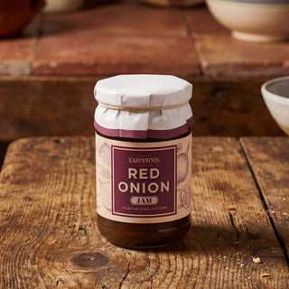 A jar of red onion jam on a wooden table