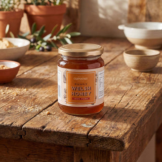A jar of Carpaninis runny Welsh honey on a wooden table
