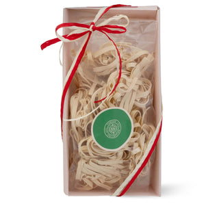 Tagliatelle pasta tray with a red ribbon and green label on a white background