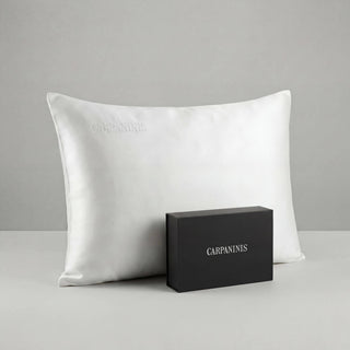 White silk pillow and black box with 'CARPANINIS' branding on a gray background