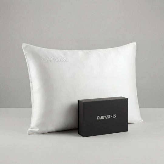 White silk pillow and black box with 'CARPANINIS' branding on a gray background