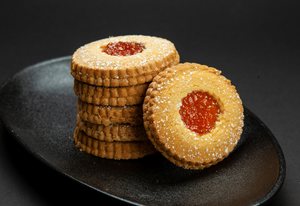 occhi di bue italian shortbread biscuits filled with apricot jam on a black plate