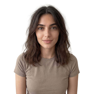 Woman wearing a beige t-shirt against a white background with slightly messy hair